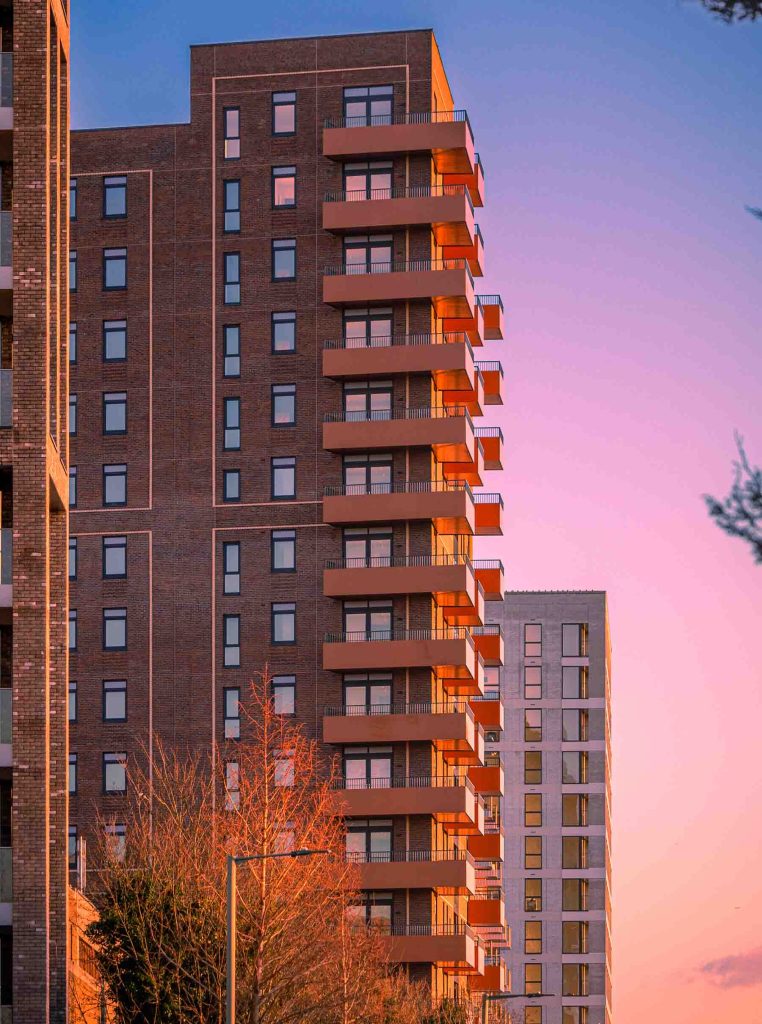 Apartment building with balconies during sunset, showcasing urban architecture and warm lighting.