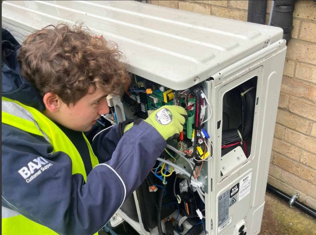 Technician working on a heat pump unit, focusing on electrical connections and system setup.