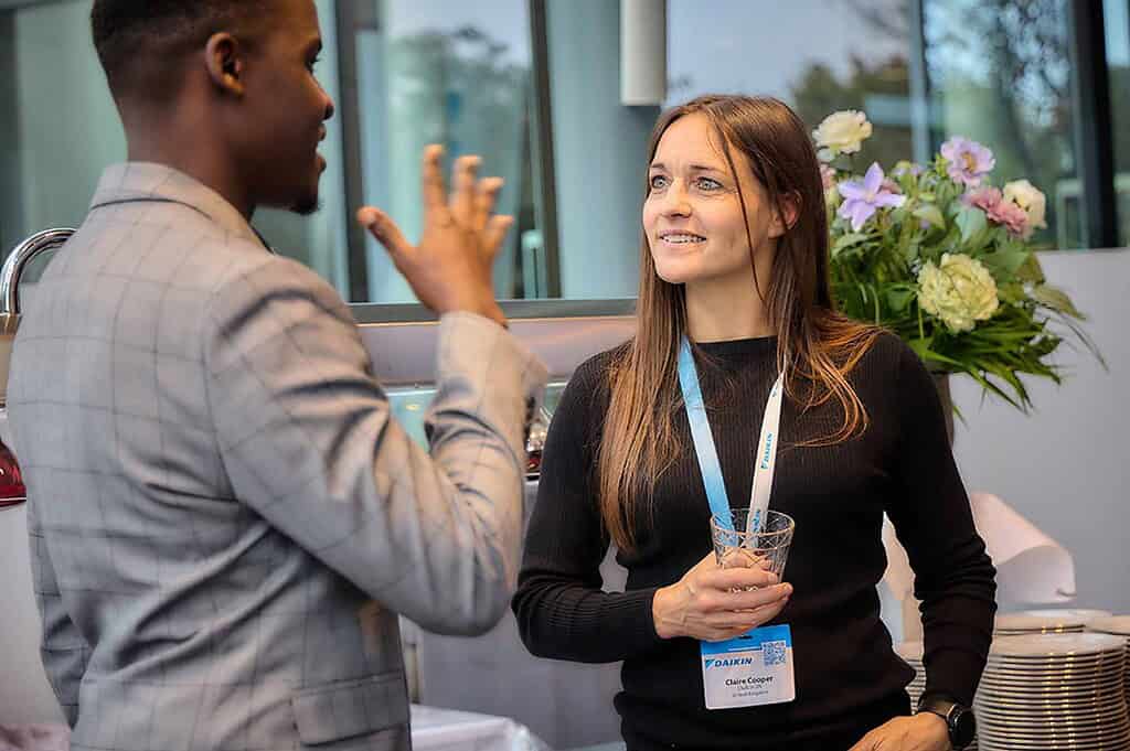 Business professionals engaging at Heat Pump News event in a modern office setting.
