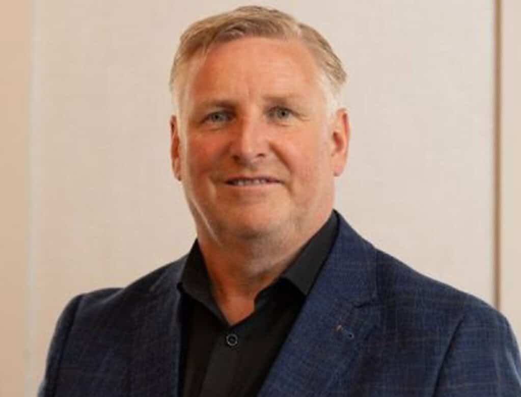 Professional man in a suit smiling, business portrait for heat pump news.