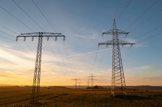 Power lines and pylons in a rural landscape during sunset, illustrating energy infrastructure.