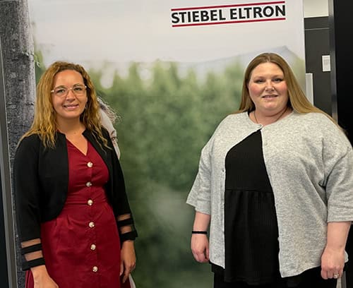 Two women standing in front of a Stiebel Eltron banner at a heat pump event.