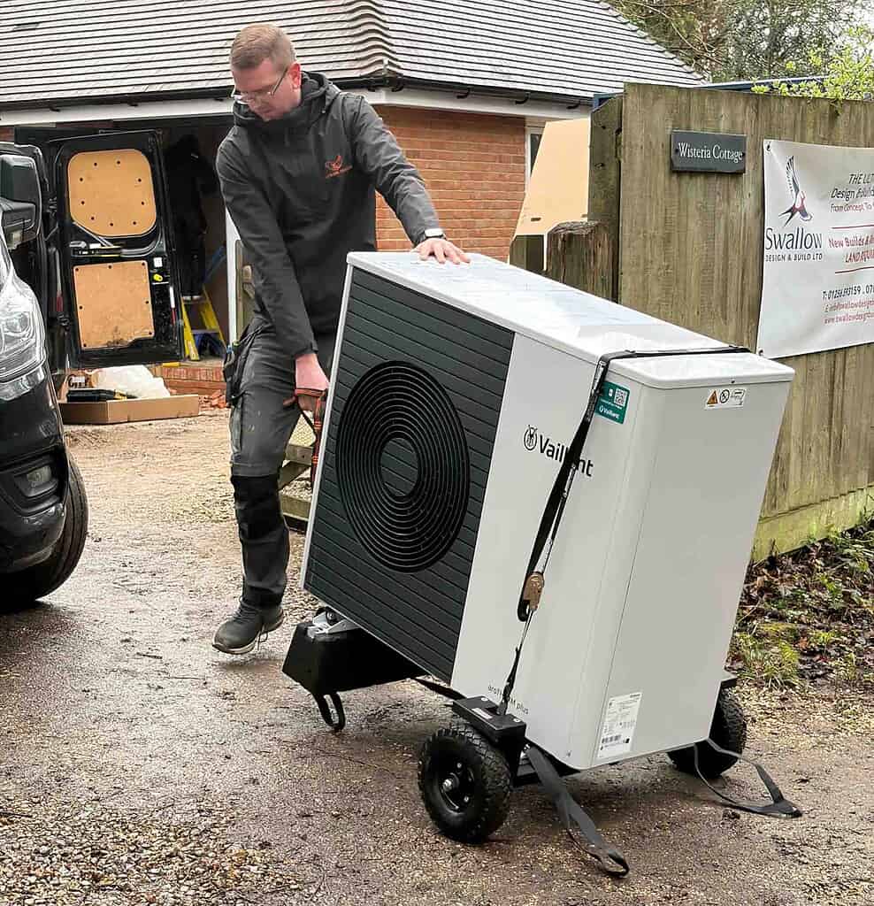 Technician installing a large Vaillant heat pump outside a residential property.