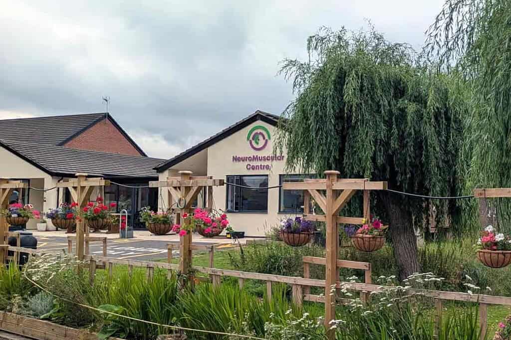 Exterior view of NeuroMuscular Centre with garden and hanging flower baskets.