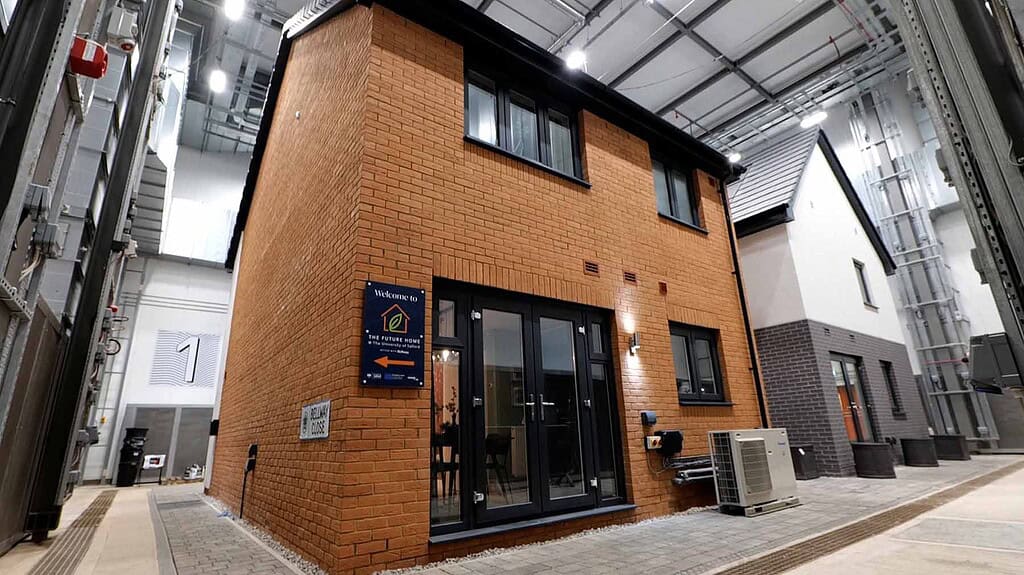 Modern brick house with heat pump system installed outside in an industrial setting.