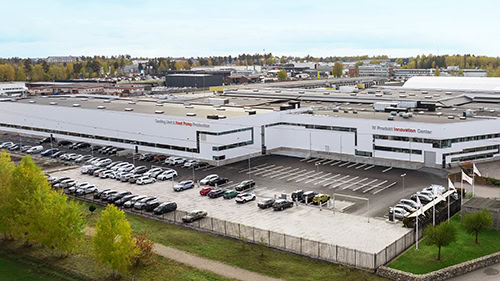 Large industrial building with parking lot and surrounding greenery.