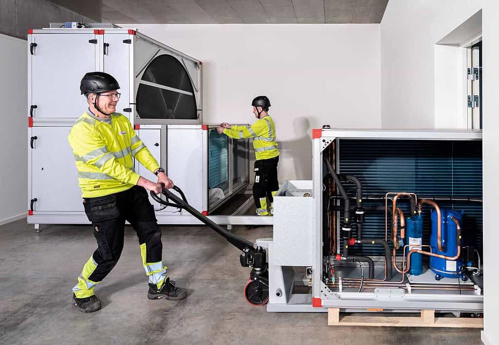 Technicians installing heat pump components in a modern indoor setting.