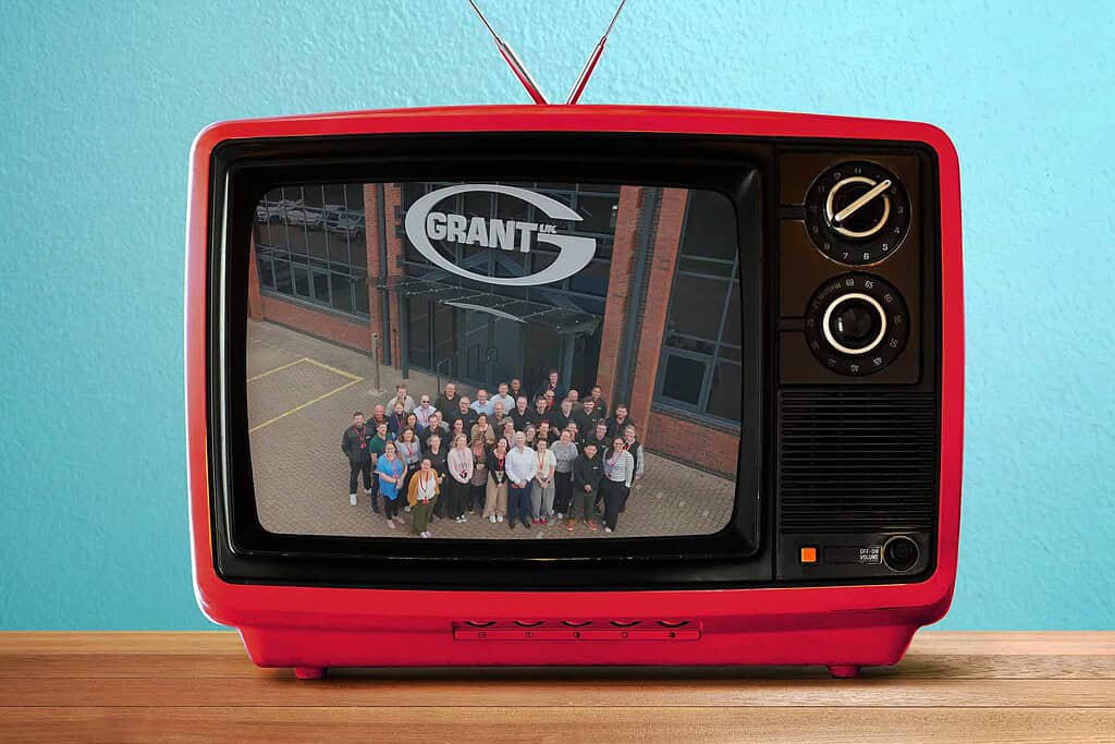Retro red TV displaying a group photo outside a building with 'Grant' logo.