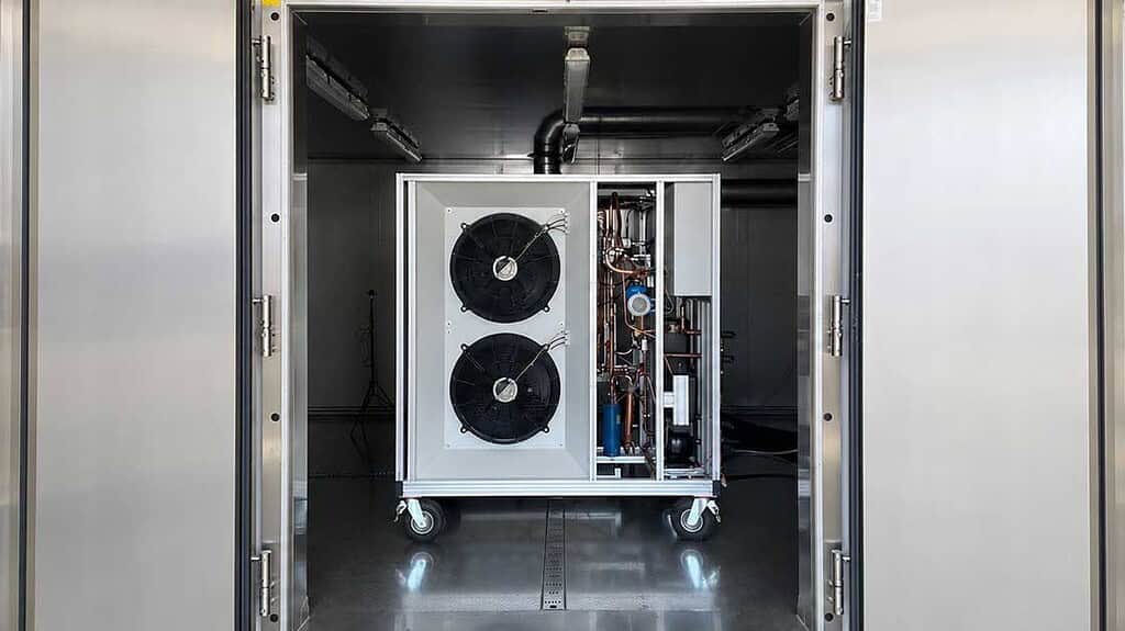 Industrial heat pump system with dual fans and copper piping inside a metal enclosure.