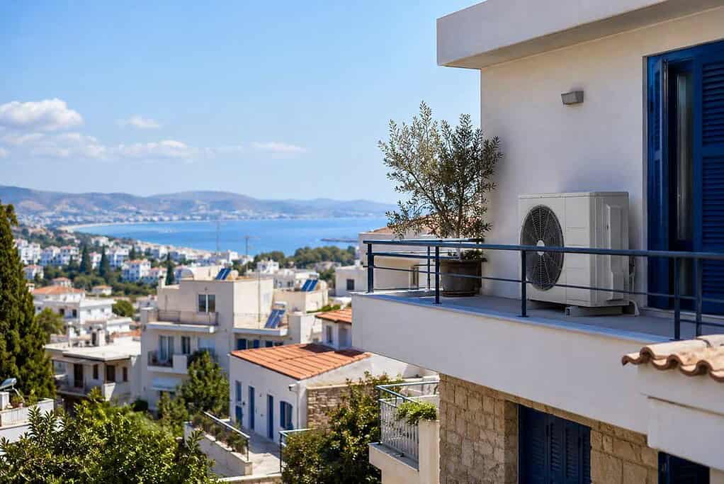 Heat pump installed on balcony of a modern apartment with city and sea view.