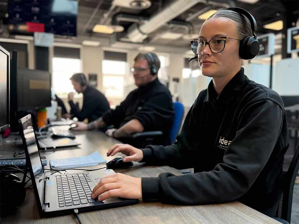 Customer service team member wearing headphones at work desk.