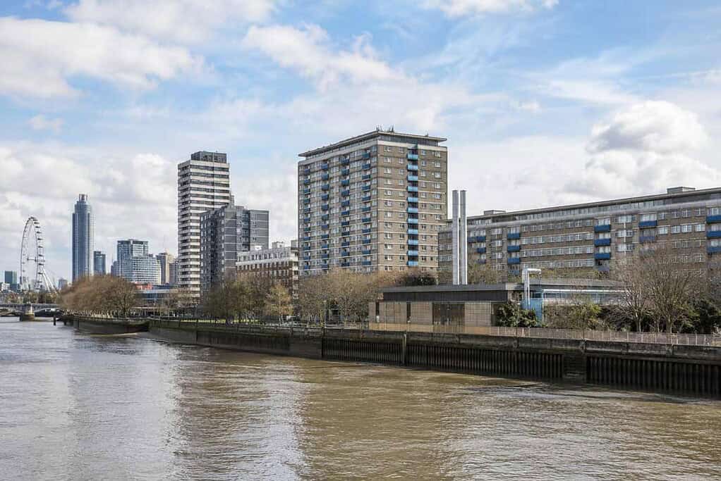 City skyline along the Thames River with modern buildings and blue sky.