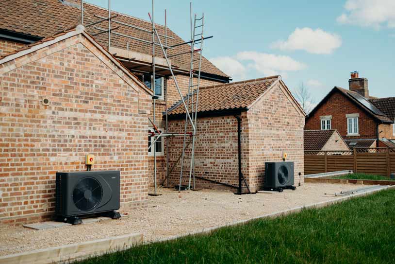 Outdoor heat pump units installed beside a brick house in Lincolnshire.