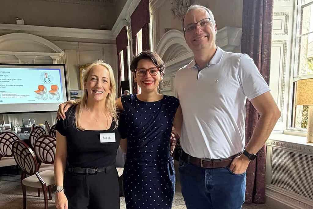 Three professionals at a conference, smiling and posing together.
