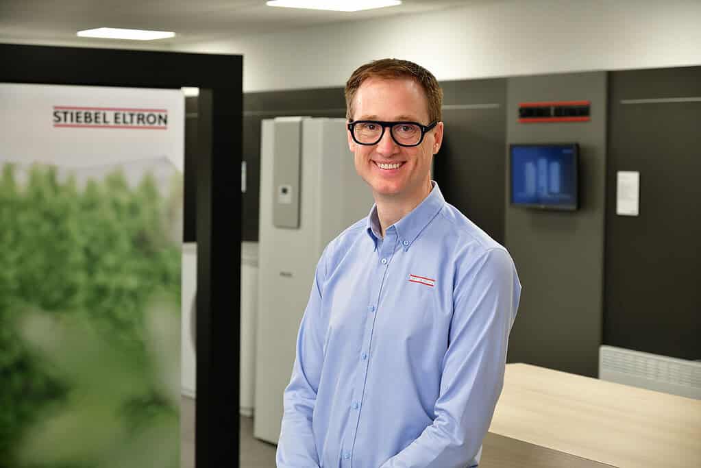 Smiling man in blue shirt at Stiebel Eltron workplace.