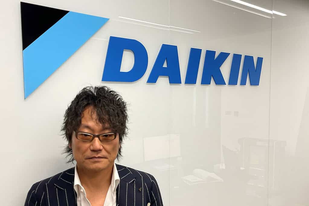 Man in front of Daikin logo at corporate office.