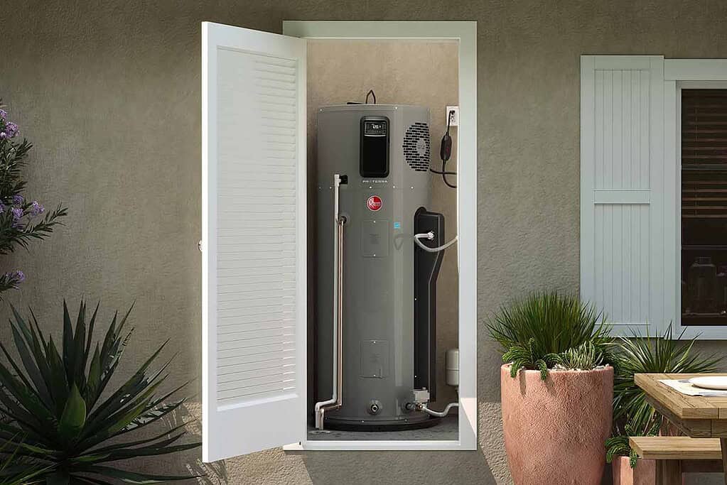 Heat pump water heater installed outdoors in a garden setting.