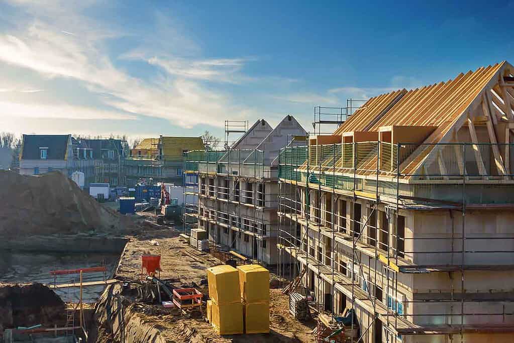 Construction site of new residential buildings with scaffolding and roofing in progress.
