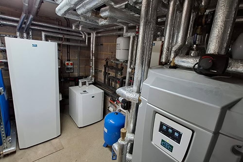 Commercial heat pump system with pipes and control units in a building utility room.