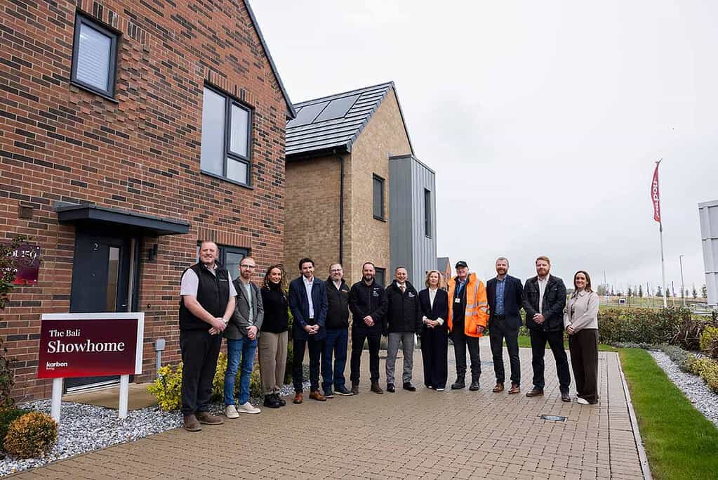 Group of professionals outside new housing development with heat pump technology.