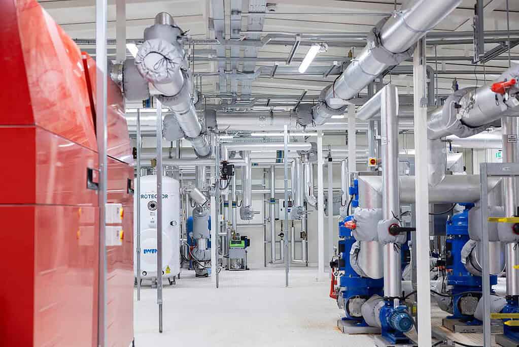 Industrial heat pump system with pipes and machinery in a clean facility.
