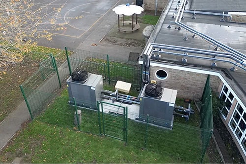 Commercial heat pump units installed outdoors with fencing for safety.