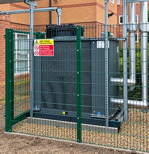 Industrial heat pump unit enclosed in safety fencing for commercial heating systems.